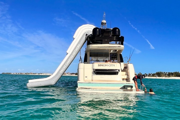 Stewardess helping a guest to board the swim platform of our yacht rental at Venetian Marina, Miami.