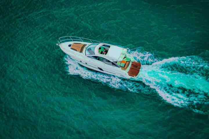 Aerial view of a white motorboat cruising on turquoise water.